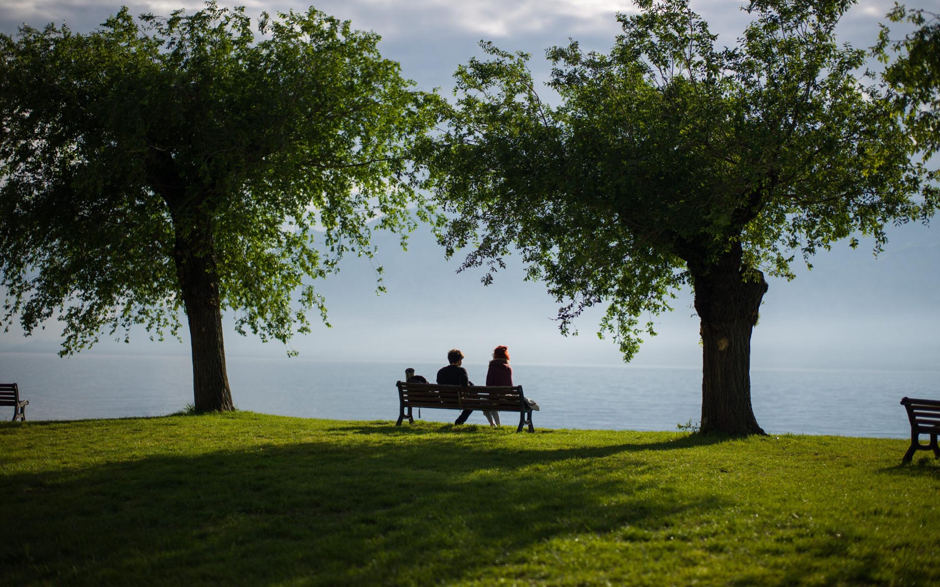 Couple sitting on a bench by the water